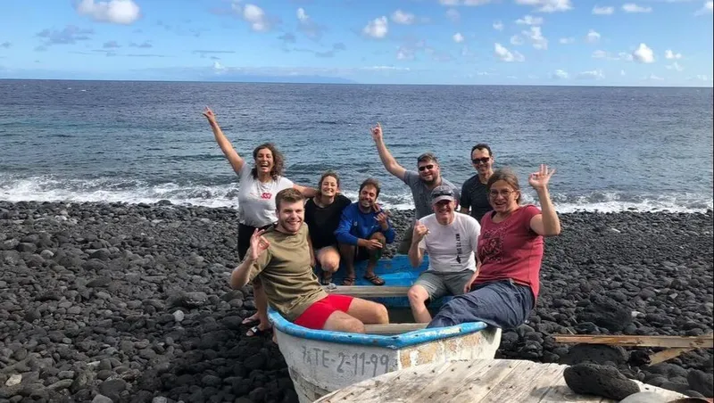 Groupe de personnes souriantes dans un petit bateau sur une plage