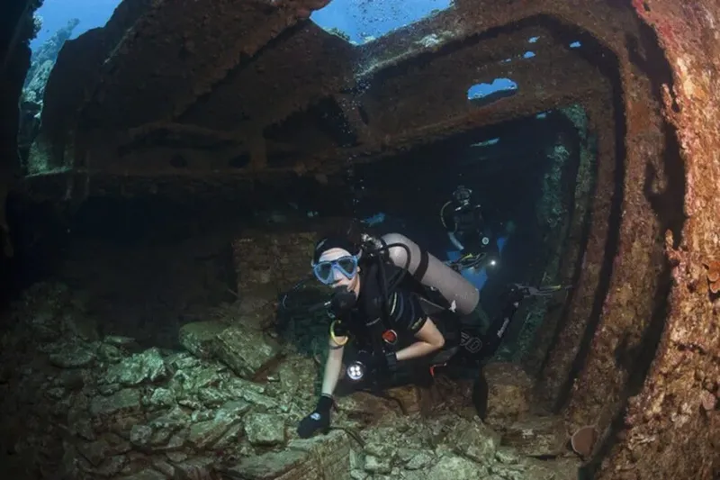Plongeur explore l'intérieur d'une épave métallique sous-marine