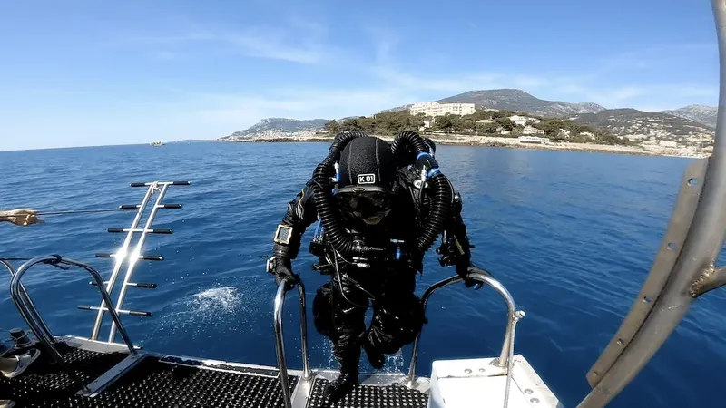 Plongeur en combinaison noire s'apprête à entrer dans l'eau depuis un bateau