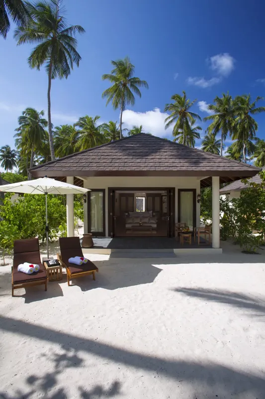 Bungalow sur plage de sable blanc avec transats et palmiers