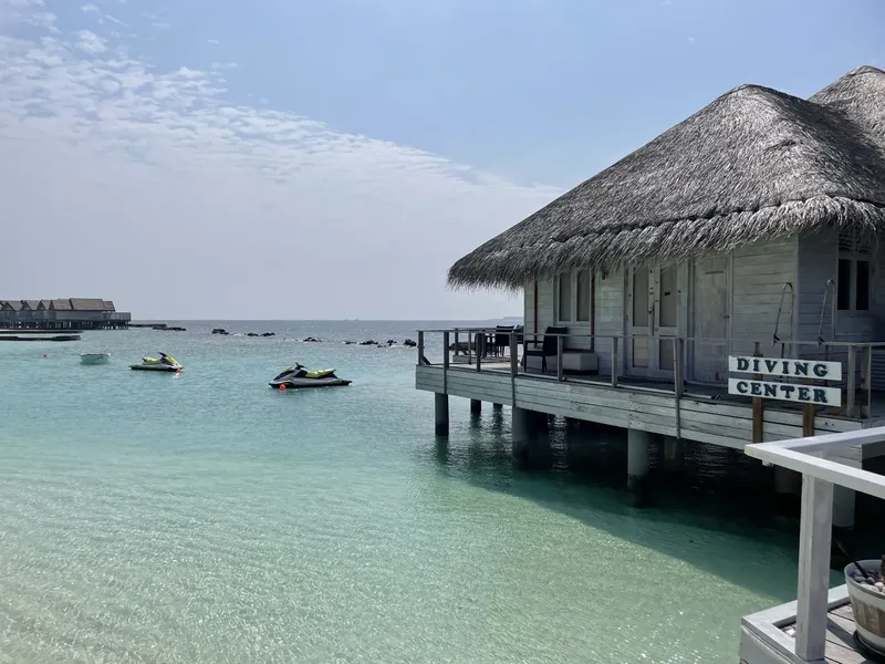Bâtiment sur pilotis avec panneau Diving Center et jet-skis en mer