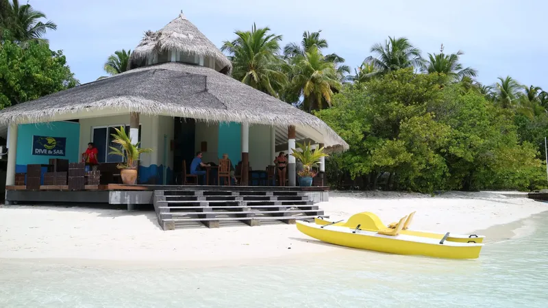 Bâtiment sur plage avec personnes assises et kayak jaune sur l'eau