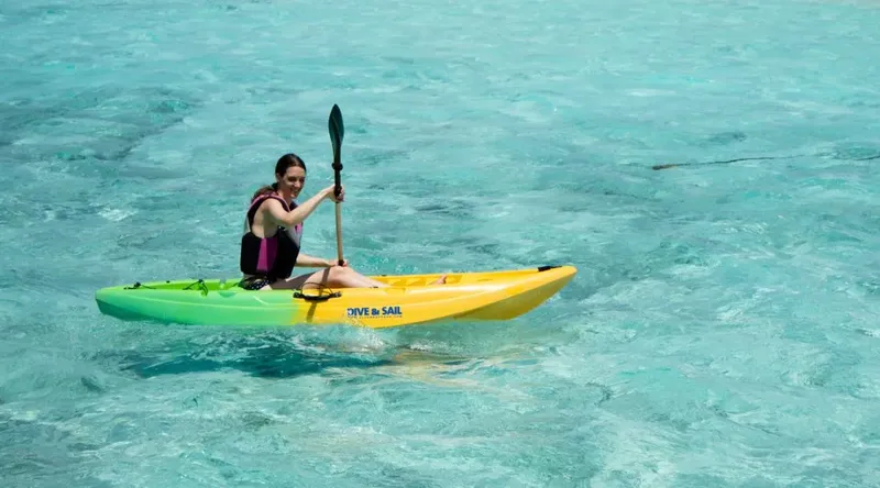 Femme pagayant en kayak sur une eau turquoise et claire