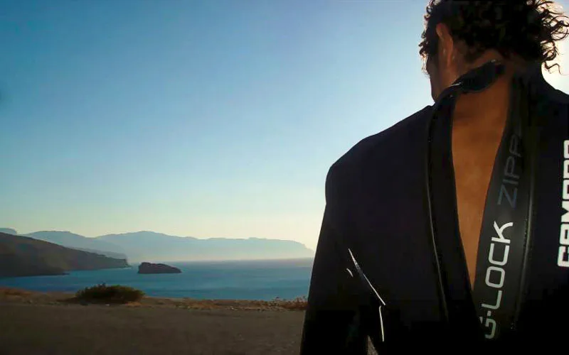 Personne en combinaison de plongée regardant la mer et les montagnes
