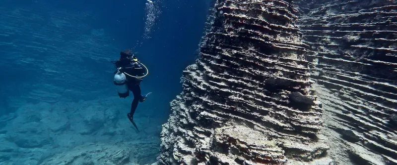 Plongeur explorant une formation rocheuse sous-marine dans une eau claire