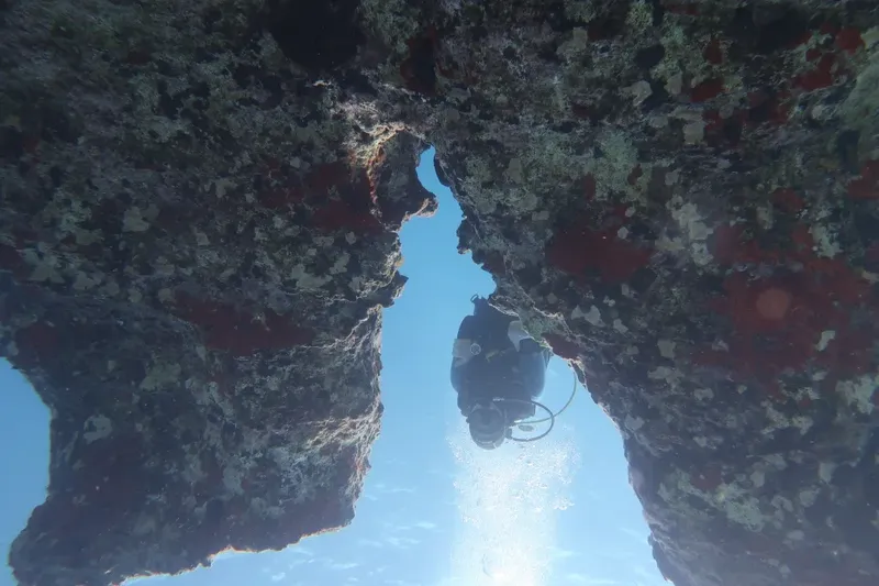 Plongeur explorant une grotte sous-marine avec lumière et roches