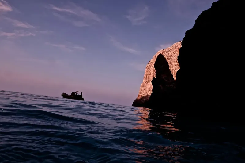 Bateau de plongée au loin, lumière sur une formation rocheuse marine