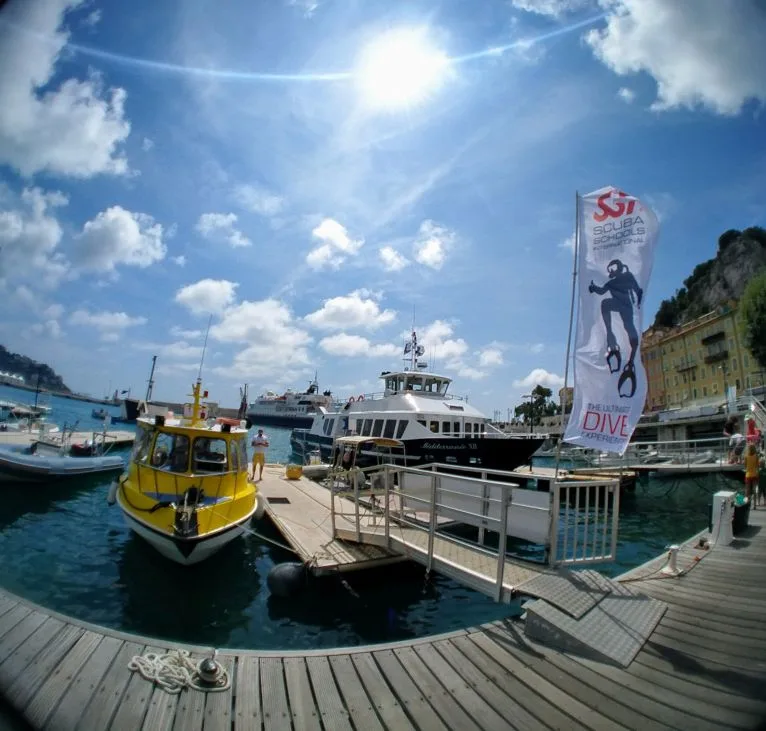 Port de plaisance ensoleillé avec bateaux amarrés et drapeau de plongée