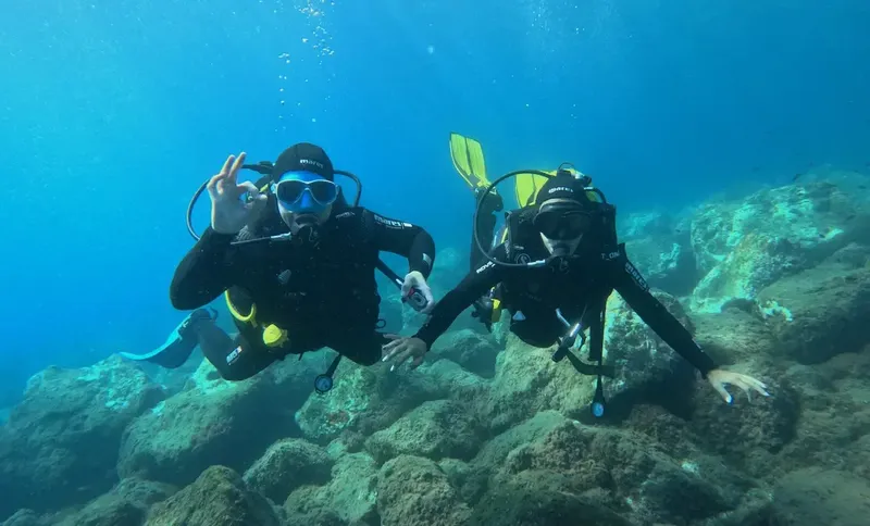 Deux plongeurs souriants font des signes de paix sous l'eau