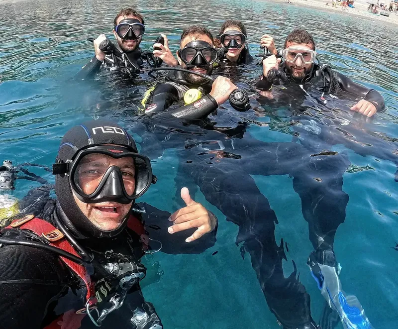 Groupe de plongeurs souriants dans une eau turquoise, signe ok