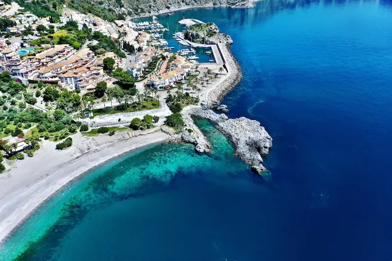 Vue aérienne d'une côte rocheuse avec un port de plaisance et une plage