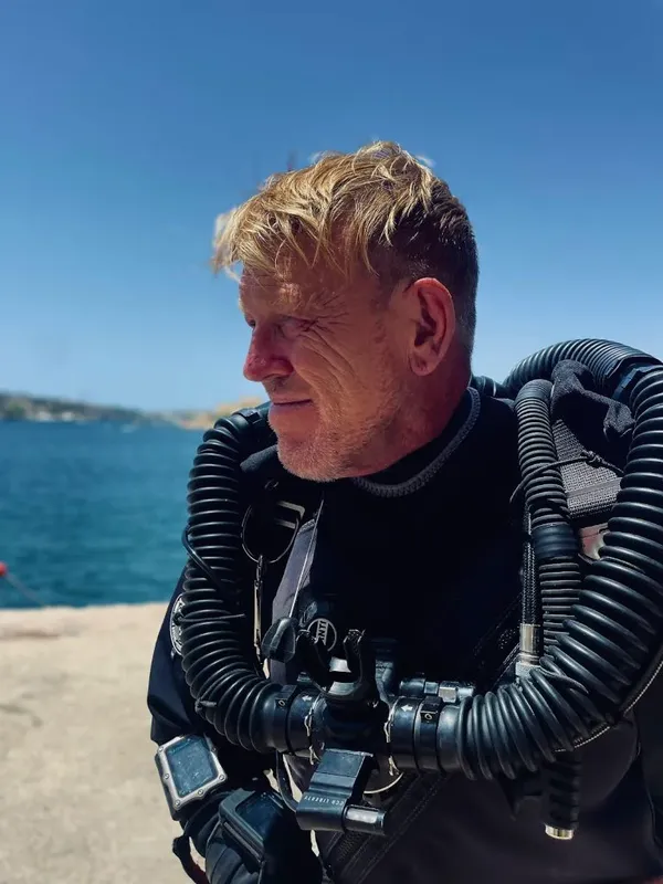 Plongeur équipé en combinaison noire, regardant au loin, mer bleue