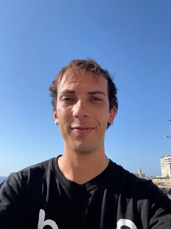 Portrait d'un jeune homme souriant devant un ciel bleu et la mer