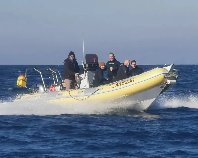 Bateau semi-rigide jaune en mer avec plusieurs personnes à bord