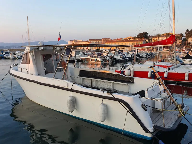Bateau de plongée amarré dans un port ensoleillé avec d'autres embarcations