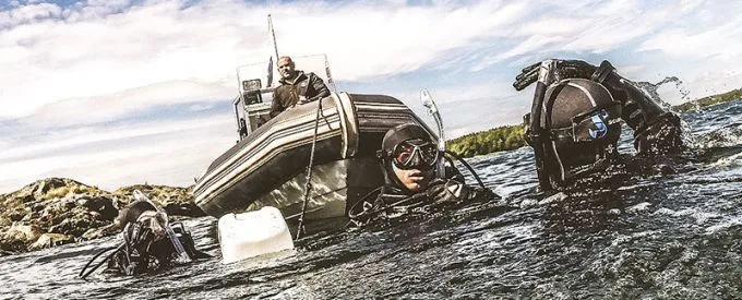 Plongeurs s'apprêtent à entrer dans l'eau depuis un bateau semi-rigide