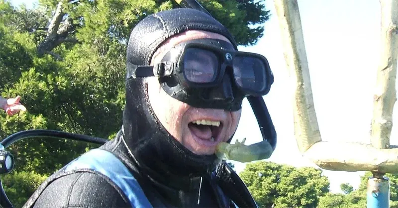 Plongeur souriant avec masque et combinaison noire en milieu aquatique