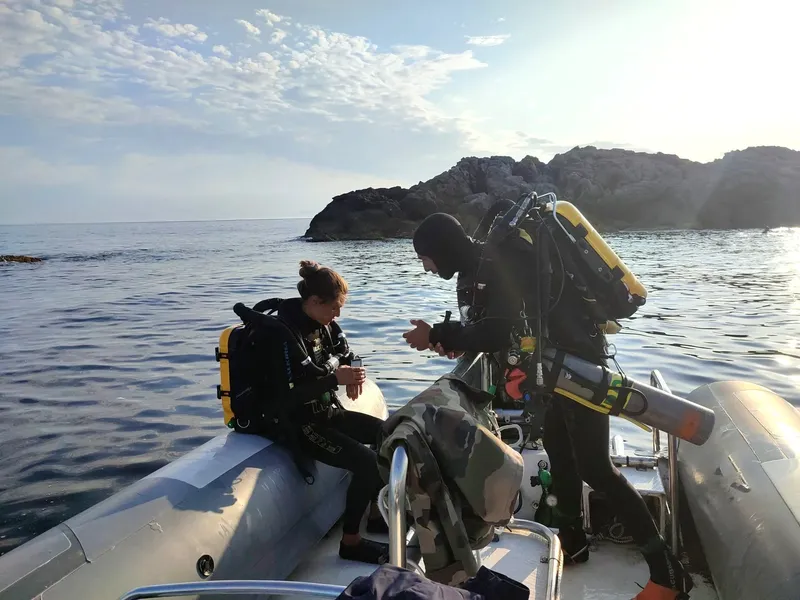 Deux plongeurs se préparent à bord d'un bateau semi-rigide en mer