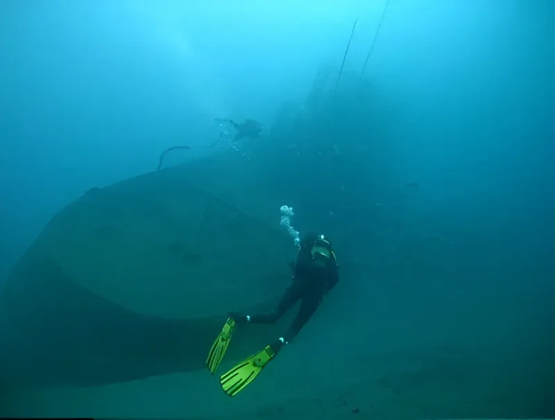 Plongeur explorant l'épave d'un grand navire sous l'eau turquoise