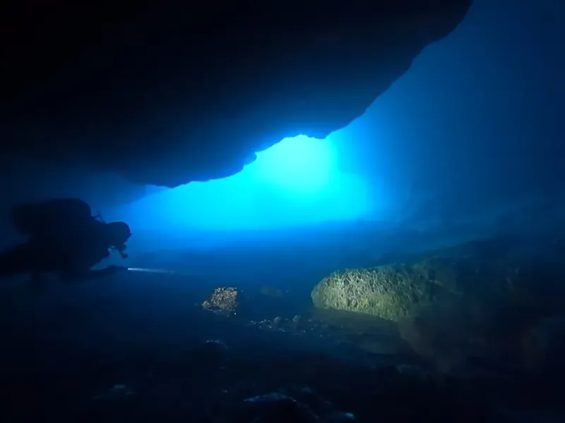 Plongeur explorant une grotte sous-marine avec une lumière vive