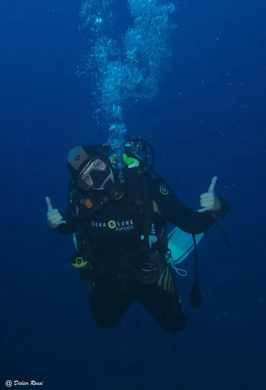 Plongeur en scaphandre sous-marin avec pouces levés dans l'eau bleue
