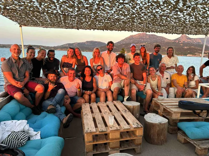 Groupe de personnes souriantes sur un bateau en mer au coucher du soleil