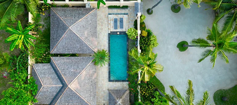 Vue aérienne d'une propriété avec piscine, végétation luxuriante et bâtiments