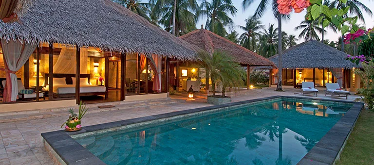 Bungalows avec toits de chaume, piscine et végétation tropicale luxuriante