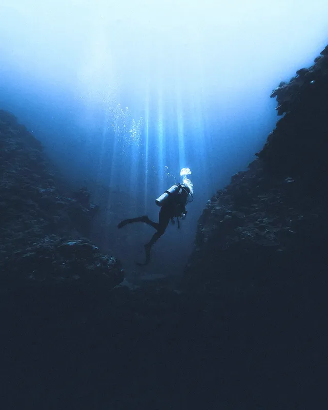 Plongeur explorant une faille sous-marine éclairée par des rayons de soleil
