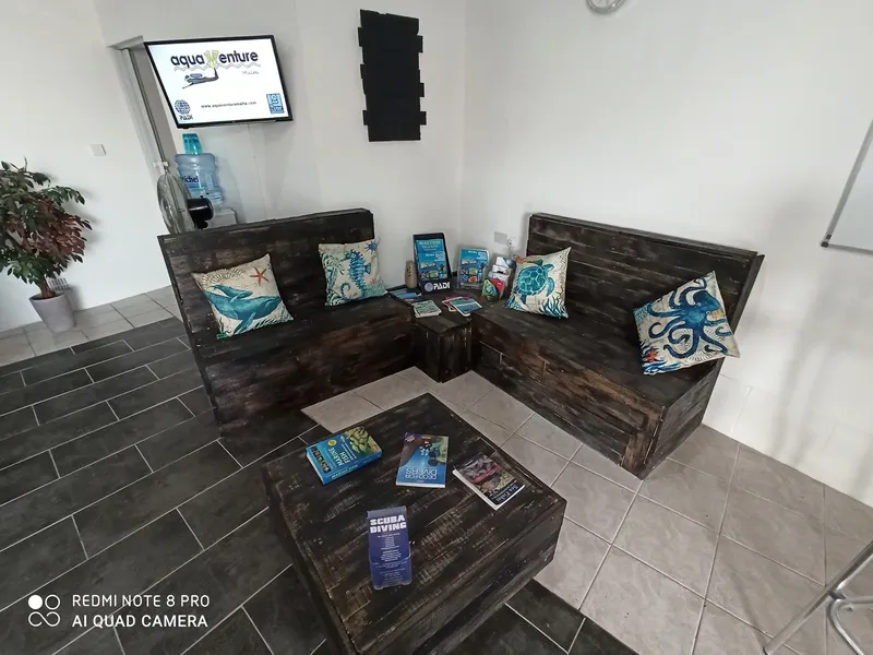 Salle d'attente d'un centre de plongée avec canapés et brochures