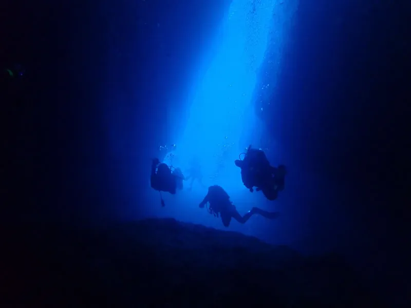 Trois plongeurs explorent un récif sous-marin dans une eau bleue