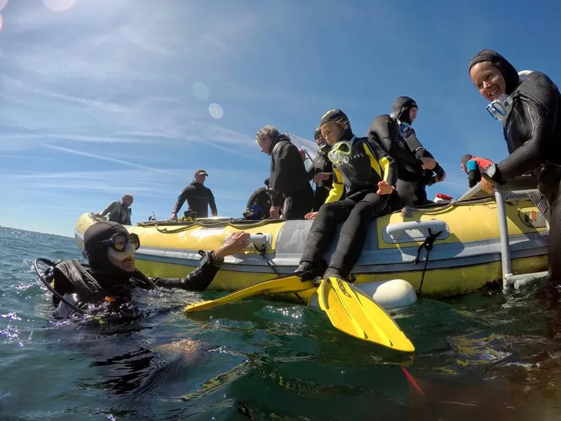 Plongeurs et nageurs dans l'eau, montent à bord d'un bateau jaune