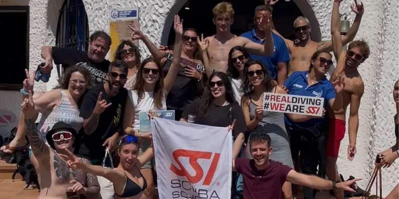 Groupe de plongeurs souriants posant avec un drapeau SSI et des pancartes