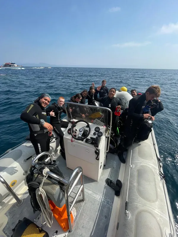 Groupe de plongeurs souriants à bord d'un bateau semi-rigide en mer