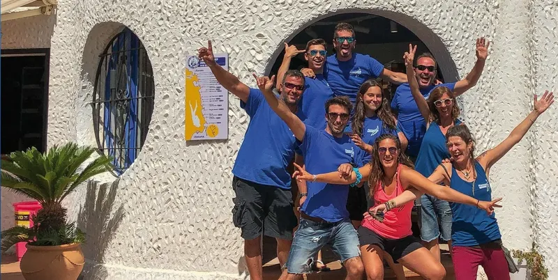 Groupe de personnes souriantes devant un centre de plongée ensoleillé