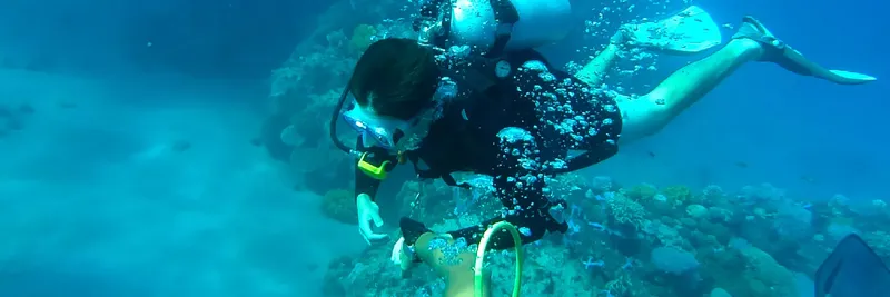 Plongeur en combinaison explore un récifal corallien bleu turquoise