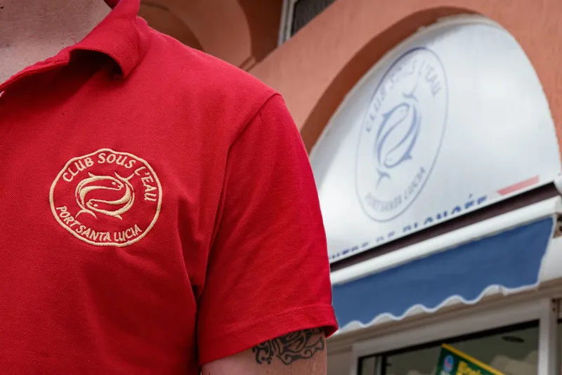Homme portant un polo rouge avec le logo d'un club de plongée
