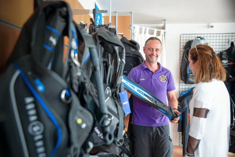 Un instructeur de plongée présente l'équipement à une cliente souriante