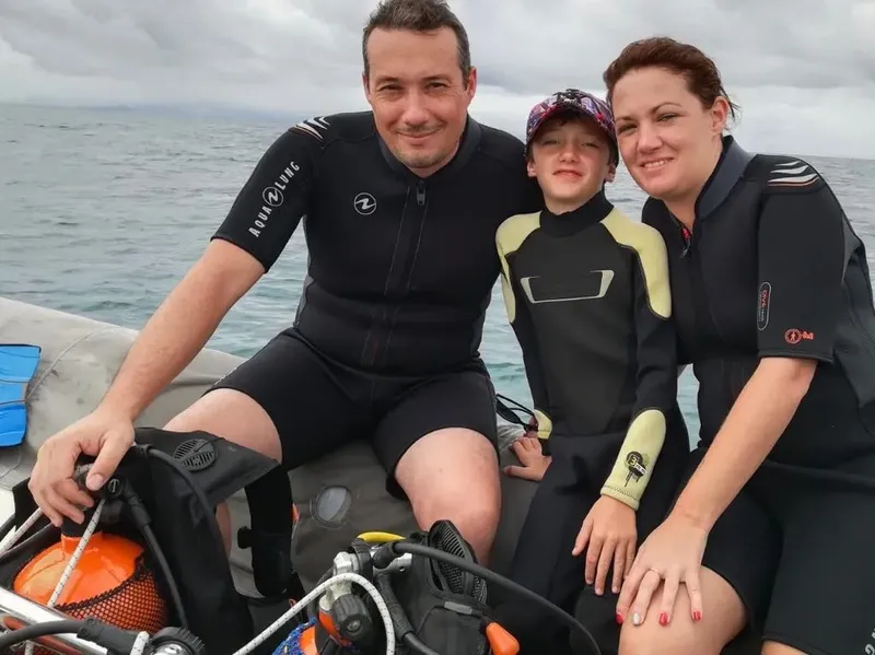 Famille souriante en combinaison de plongée sur un bateau pneumatique