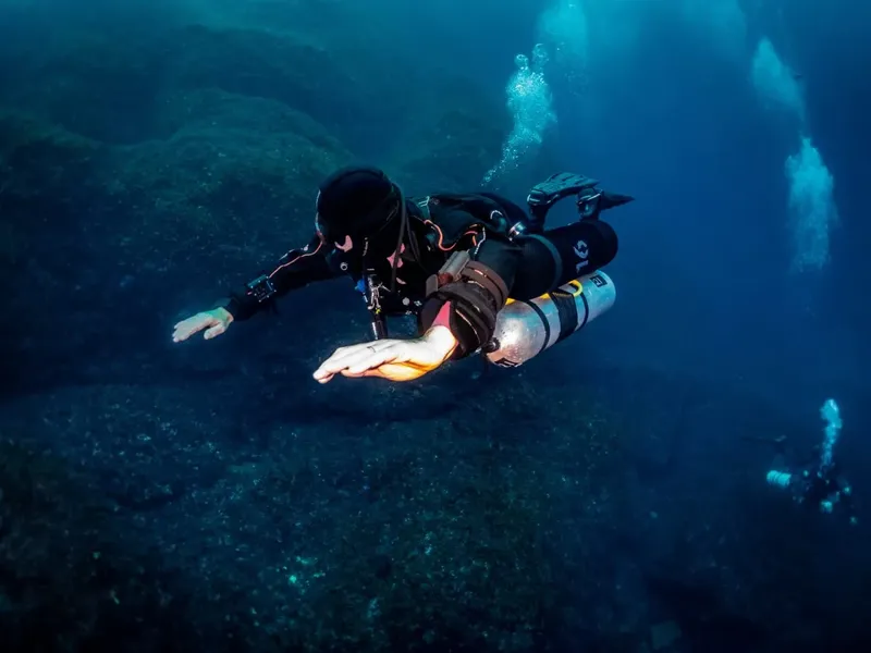Plongeur en combinaison noire nageant dans une eau bleue claire