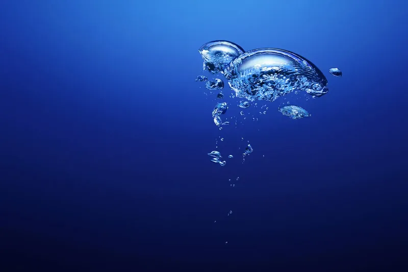 Bulles d'air remontant dans l'eau bleue profonde, ambiance calme