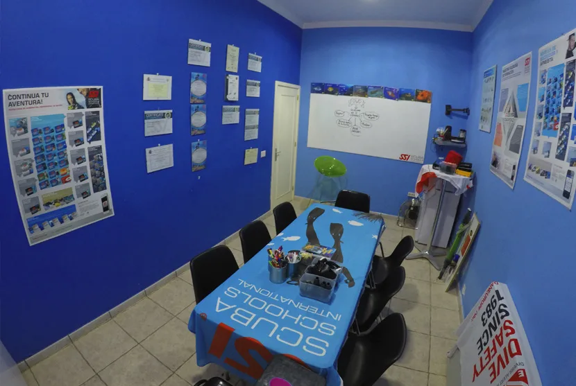 Salle de cours de plongée avec des tableaux, une table et des chaises