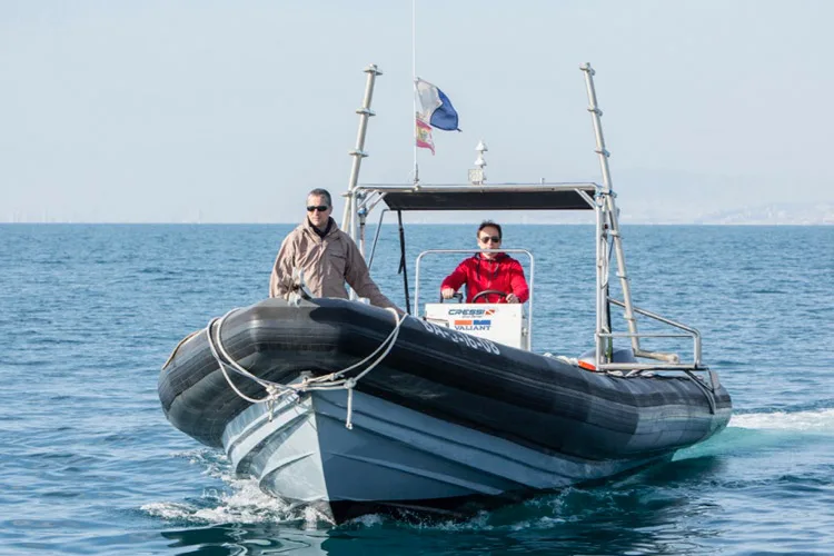 Deux personnes à bord d'un semi-rigide naviguant sur une mer bleue