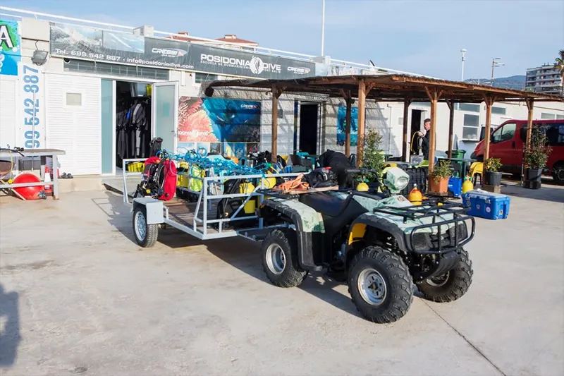Centre de plongée avec équipement, quad et personnes devant la structure