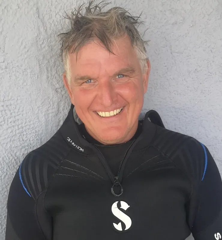 Portrait d'un homme souriant portant une combinaison de plongée noire