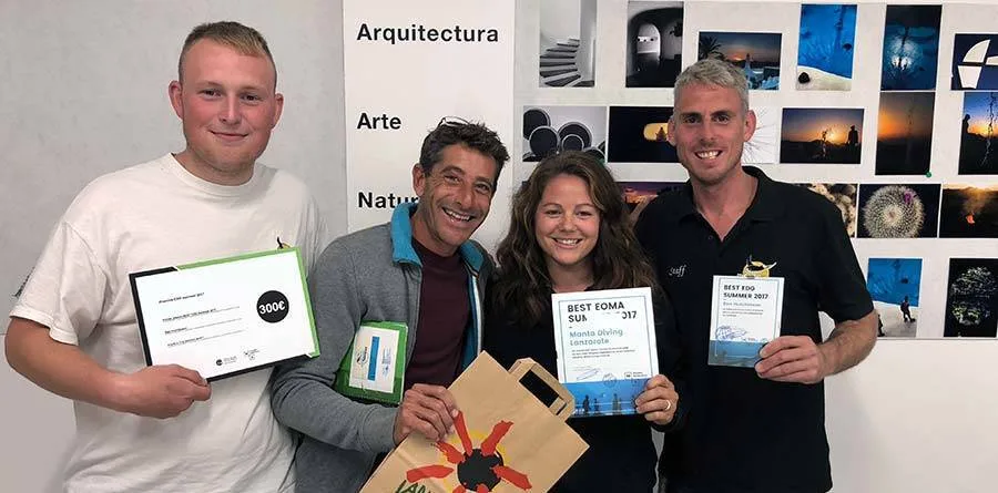 Quatre personnes souriantes présentent des certificats et des prix gagnés