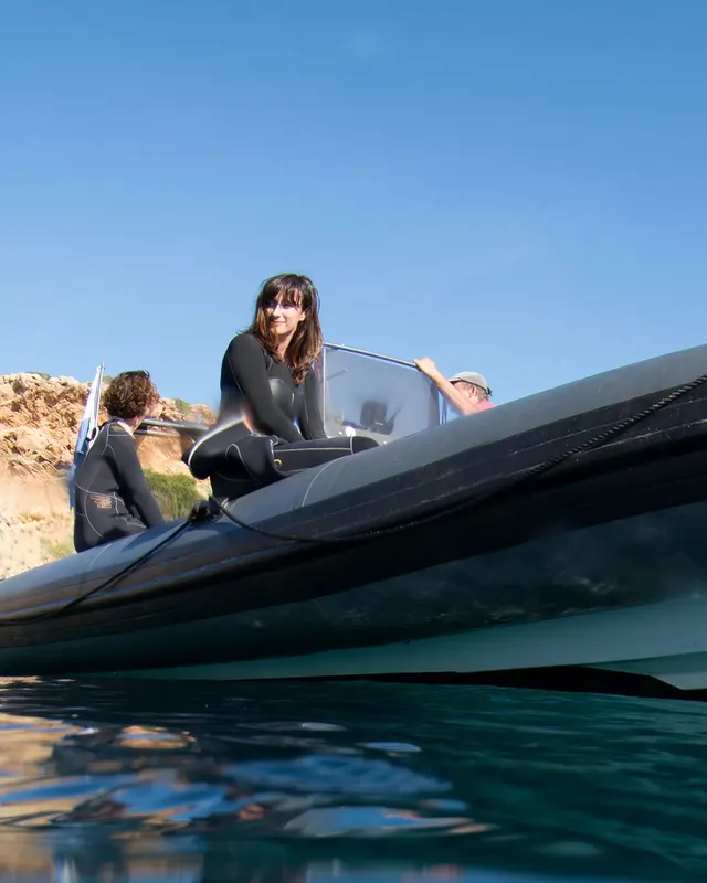 Trois personnes en combinaison de plongée à bord d'un bateau noir