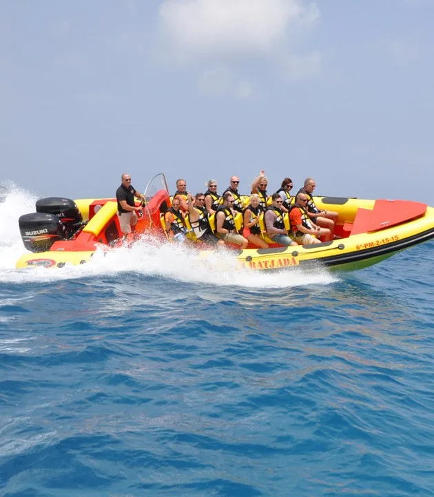 Groupe de personnes à bord d'un bateau semi-rigide jaune et rouge en mer