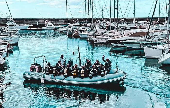 Plongeurs sur un bateau semi-rigide dans un port ensoleillé