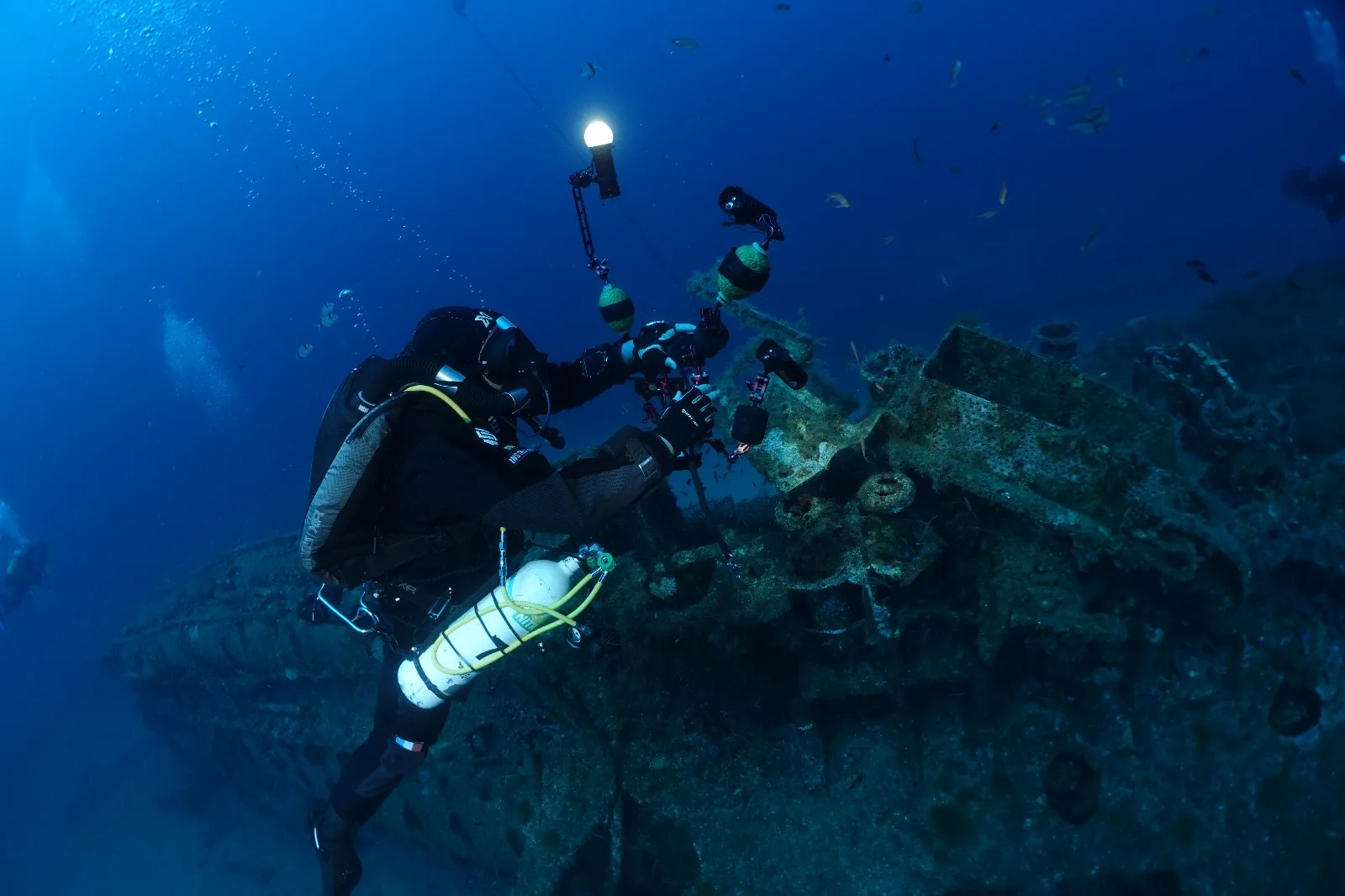 Plongeur manipule un appareil photo sous-marin près d'une épave rouillée